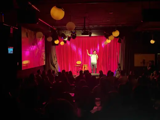 Dovi Neuburger performing in a packed pink-lit room
