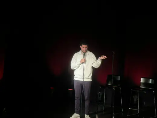 Wide shot of Dovi Neuburger performing on a dark stage