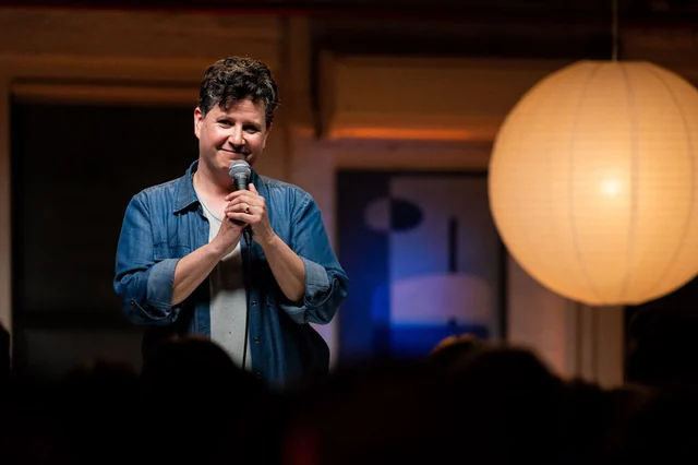 Liz Glazer performing stand-up with a microphone