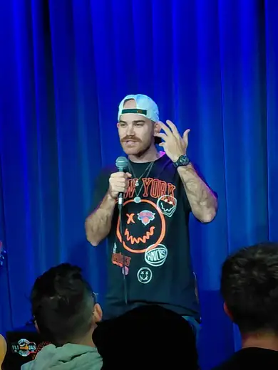 Comedian performing in a cap at Shabbos Night Live